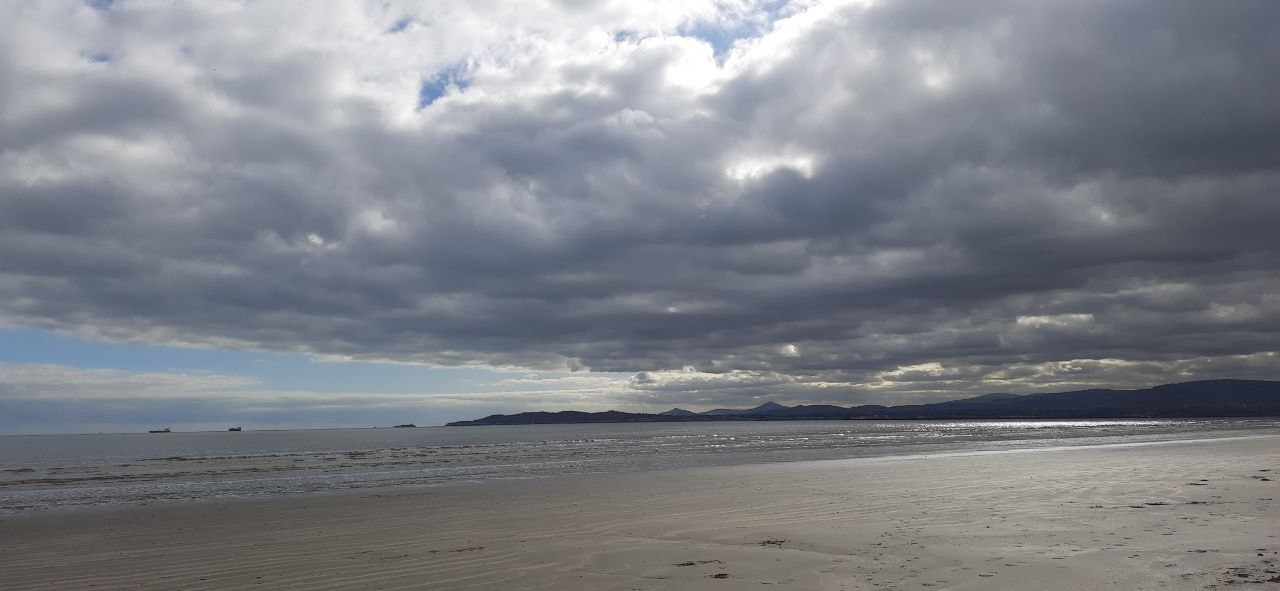 a landscape view of the beach with dark clouds in the sky at bull island in Dublin bay